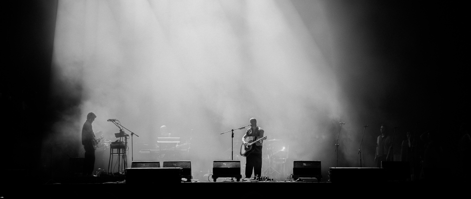 Krzysztof Zalewski na scenie - muzyk trzyma w ręku gitarę i śpiewa do mikrofonu